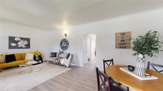 living room featuring arched walkways, light wood finished floors, and baseboards