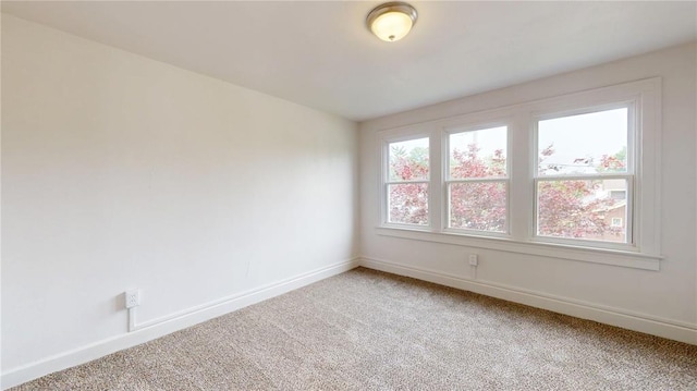 empty room featuring light colored carpet and baseboards
