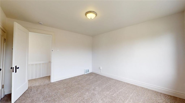 carpeted spare room featuring baseboards and a smoke detector