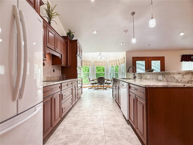 kitchen with freestanding refrigerator, a sink, dishwashing machine, decorative light fixtures, and oven