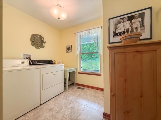 clothes washing area with washing machine and dryer, baseboards, and light tile patterned floors