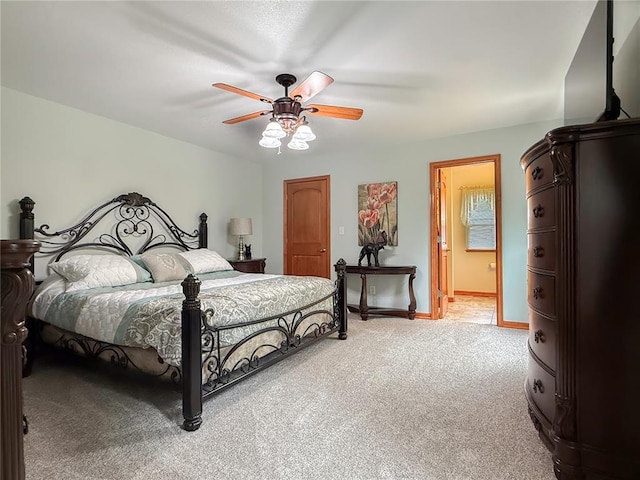 bedroom featuring light colored carpet, a ceiling fan, ensuite bathroom, and baseboards