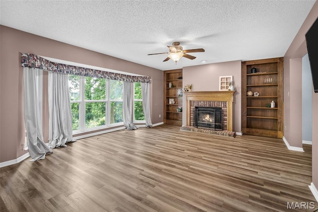 881 Sara Beth Ct, Saint Peters, MO 63376 - unfurnished living room featuring a textured ceiling, a brick fireplace, ceiling fan, wood finished floors, and built in features