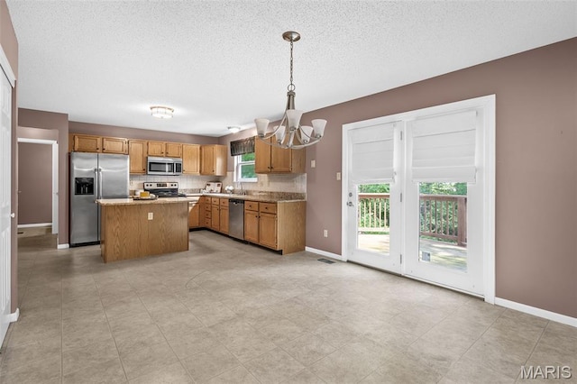 881 Sara Beth Ct, Saint Peters, MO 63376 - kitchen featuring stainless steel appliances, a chandelier, plenty of natural light, a kitchen island, and a textured ceiling