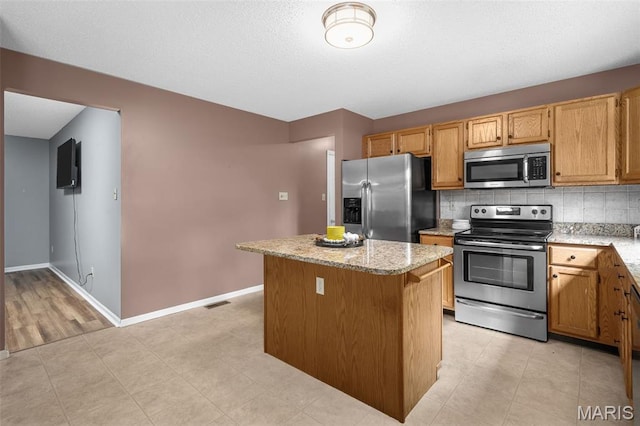 881 Sara Beth Ct, Saint Peters, MO 63376 - kitchen featuring stainless steel appliances, a kitchen island, backsplash, and light stone countertops