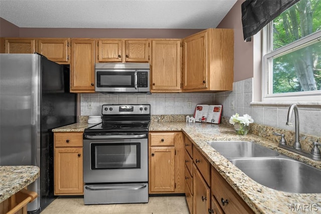 881 Sara Beth Ct, Saint Peters, MO 63376 - kitchen with appliances with stainless steel finishes, light tile patterned floors, decorative backsplash, and light stone counters