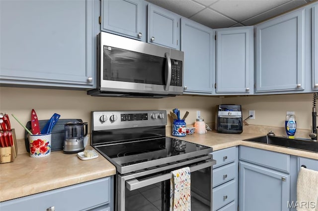 15092 State Highway Ad, Dexter, MO 63841 - kitchen featuring stainless steel appliances, light countertops, blue cabinetry, and a drop ceiling