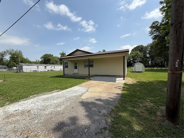 414 Jackson, Morehouse, MO 63868 - view of front facade featuring a storage unit, concrete driveway, a front lawn, and an outdoor structure