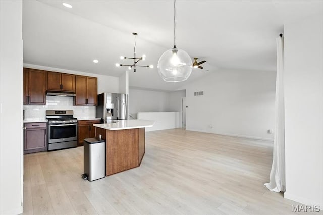 2112 Windswept Farms Dr, Eureka, MO 63025 - kitchen with appliances with stainless steel finishes, under cabinet range hood, vaulted ceiling, light countertops, and tasteful backsplash