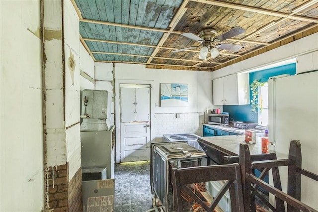 kitchen featuring stainless steel microwave, wood ceiling, ceiling fan, freestanding refrigerator, and white cabinets