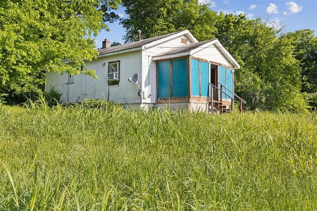 view of front of property with a chimney, entry steps, cooling unit, and a sunroom