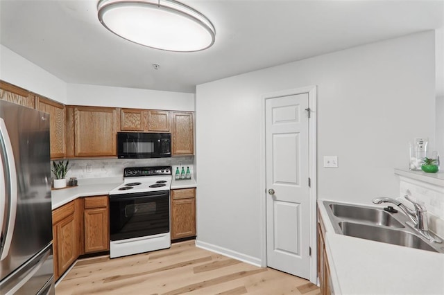 1625 Forest Springs Ln Unit A, Ballwin, MO 63021 - kitchen with black microwave, freestanding refrigerator, white electric stove, a sink, and light wood-style flooring