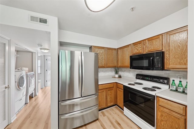 1625 Forest Springs Ln Unit A, Ballwin, MO 63021 - kitchen featuring freestanding refrigerator, range with electric stovetop, black microwave, washing machine and clothes dryer, and light wood finished floors