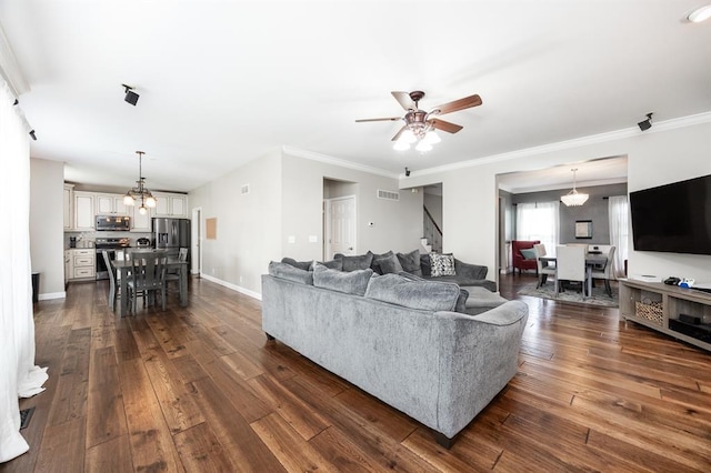 living area featuring stairway, a ceiling fan, dark wood-style flooring, a chandelier, and ornamental molding
