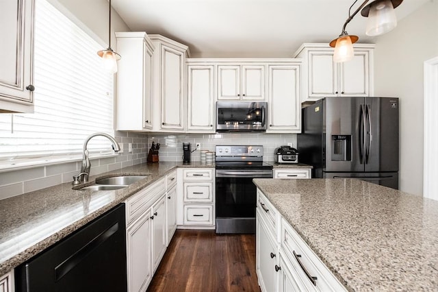 kitchen featuring appliances with stainless steel finishes, a sink, tasteful backsplash, dark wood-style flooring, and light stone countertops