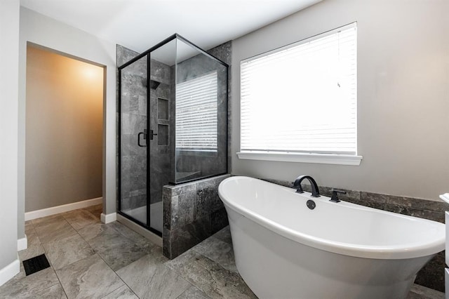 bathroom with a stall shower, a soaking tub, and plenty of natural light