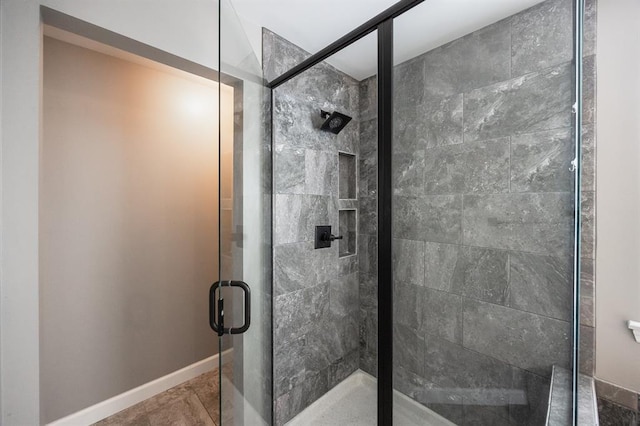 full bathroom with a shower stall and baseboards