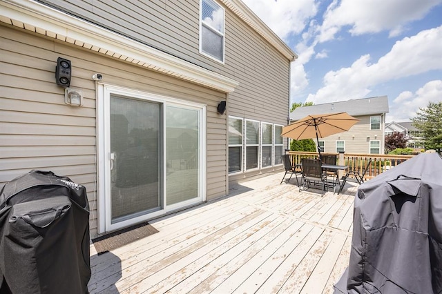 wooden terrace featuring outdoor dining area and a grill