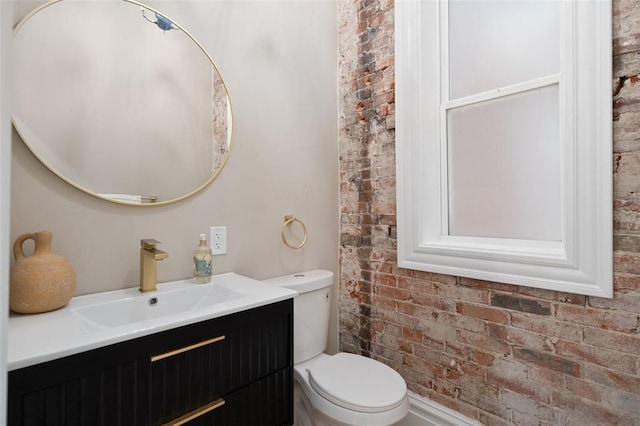 3235 S Jefferson Ave, Saint Louis, MO 63118 - bathroom featuring toilet, vanity, and brick wall