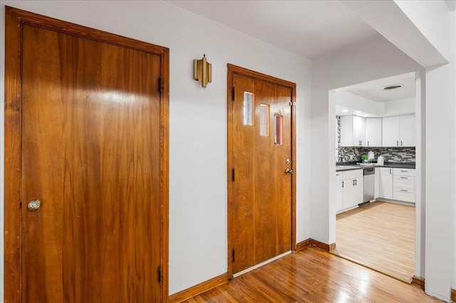 hall featuring light wood finished floors and baseboards
