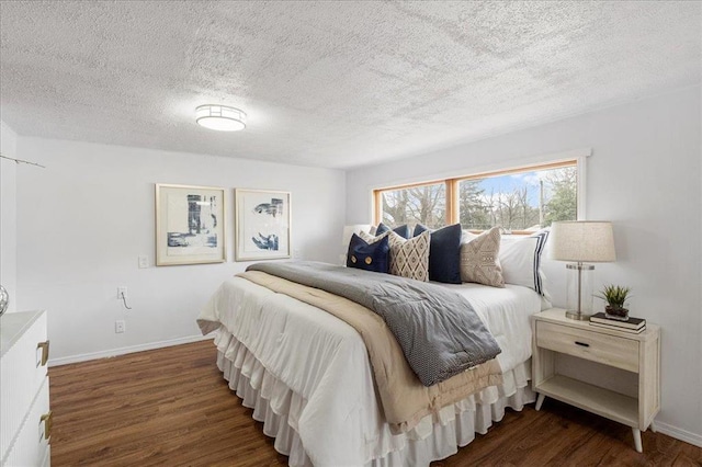 bedroom with dark wood-style floors, a textured ceiling, and baseboards