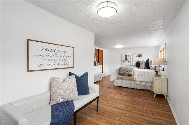 bedroom featuring a textured ceiling, wood finished floors, and baseboards