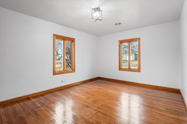 spare room with healthy amount of natural light, wood finished floors, and baseboards