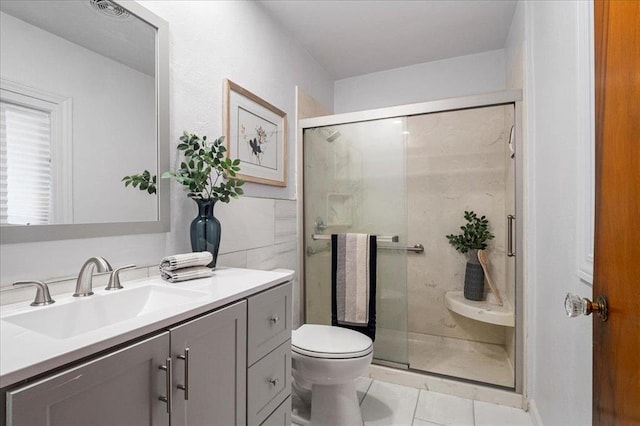 bathroom featuring tile patterned flooring, toilet, vanity, and a shower stall