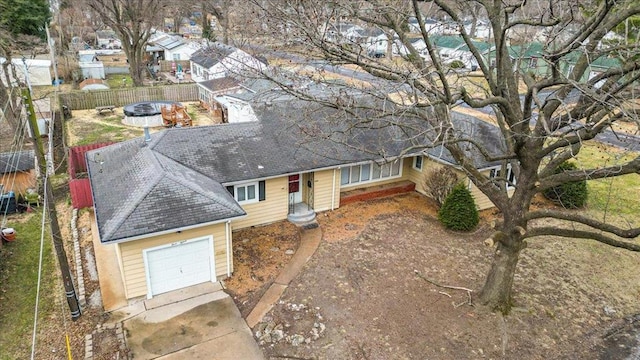 view of front of house featuring roof with shingles, fence, and driveway