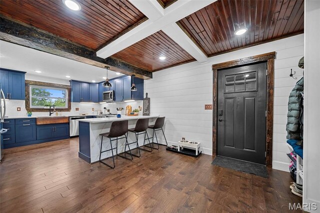 425 Cedar Ln, Wentzville, MO 63385 - kitchen featuring blue cabinets, stainless steel appliances, a peninsula, light countertops, and dark wood finished floors