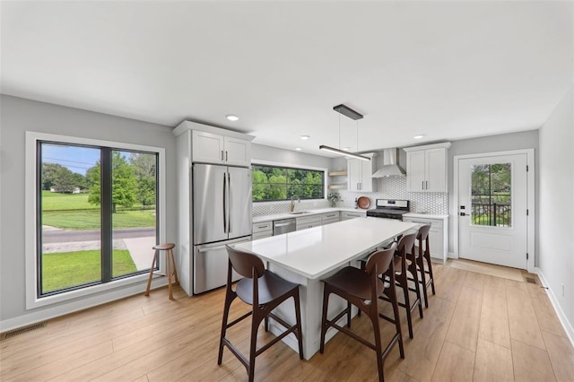 527 W Lake Dr, Edwardsville, IL 62025 - kitchen featuring stainless steel appliances, wall chimney range hood, a sink, light countertops, and decorative backsplash