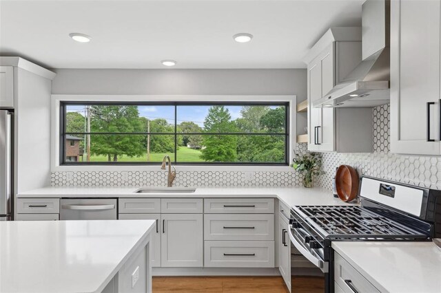 527 W Lake Dr, Edwardsville, IL 62025 - kitchen featuring stainless steel appliances, wall chimney exhaust hood, a sink, light countertops, and recessed lighting
