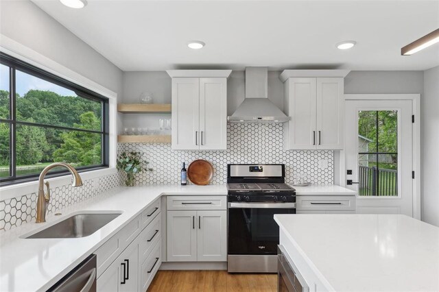 527 W Lake Dr, Edwardsville, IL 62025 - kitchen with wall chimney exhaust hood, appliances with stainless steel finishes, a sink, light countertops, and white cabinetry