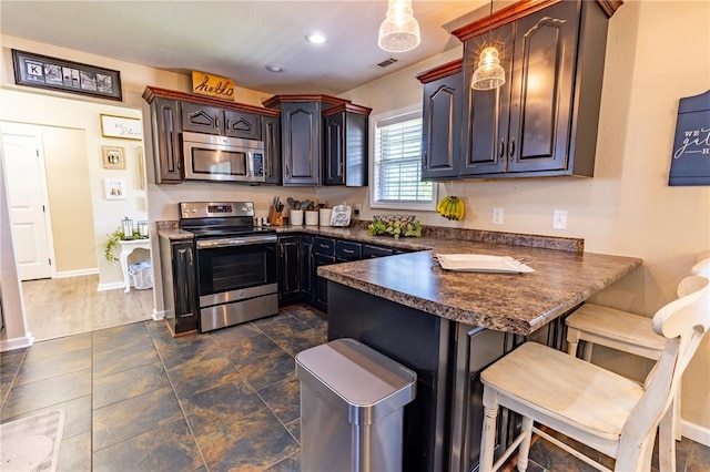 1114 Daffodil St, Sikeston, MO 63801 - kitchen featuring appliances with stainless steel finishes, dark countertops, a peninsula, a breakfast bar area, and baseboards