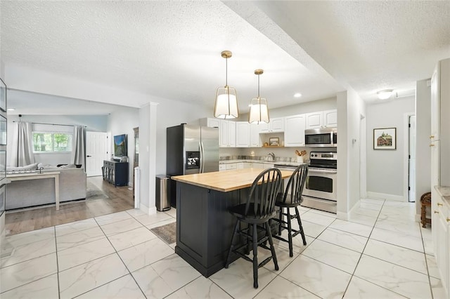 636 Parker Dr, Ballwin, MO 63021 - kitchen with stainless steel appliances, wooden counters, light marble finish floors, a textured ceiling, and open floor plan
