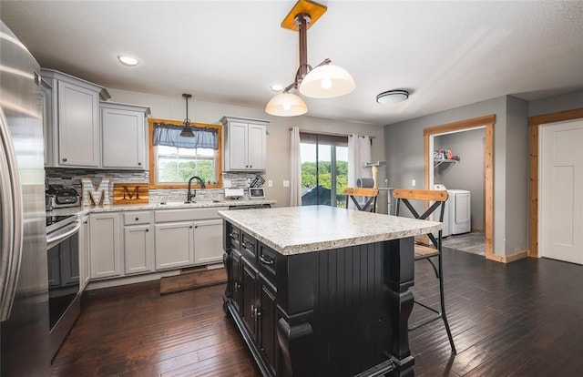 20998 Halifax Dr, Saint Robert, MO 65584 - kitchen featuring a sink, a kitchen breakfast bar, stainless steel appliances, decorative backsplash, and washer / clothes dryer