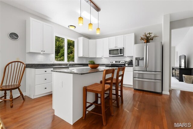943 Sheffield Forest Ct, Saint Louis, MO 63021 - kitchen with stainless steel appliances, dark countertops, dark wood-style flooring, a breakfast bar, and white cabinets