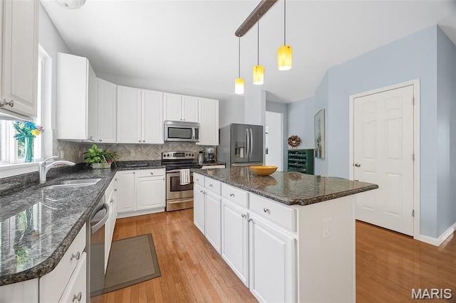 943 Sheffield Forest Ct, Saint Louis, MO 63021 - kitchen with appliances with stainless steel finishes, a kitchen island, light wood-style floors, white cabinetry, and decorative backsplash