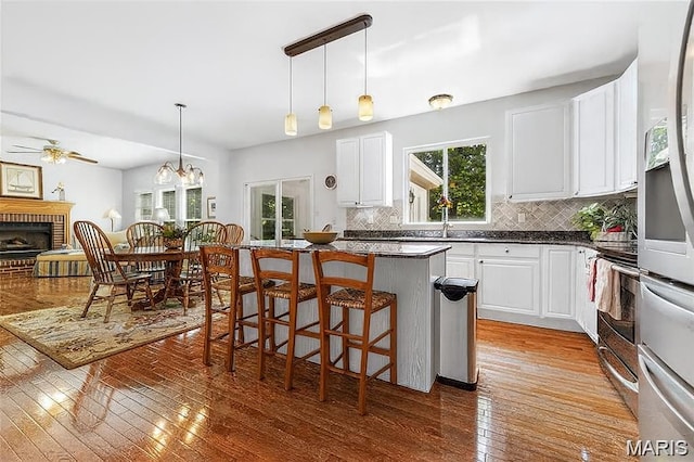 943 Sheffield Forest Ct, Saint Louis, MO 63021 - kitchen with stainless steel appliances, decorative backsplash, a kitchen breakfast bar, a brick fireplace, and ceiling fan