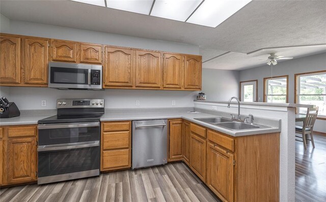 12755 Echo Ln, Plato, MO 65552 - kitchen with stainless steel appliances, a sink, a peninsula, light wood finished floors, and brown cabinets