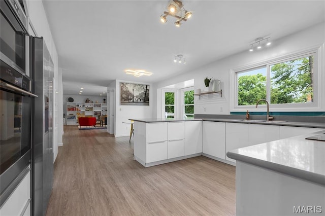 16027 Clarkson Woods Dr, Chesterfield, MO 63017 - kitchen featuring modern cabinets, white cabinetry, light wood finished floors, open shelves, and a peninsula