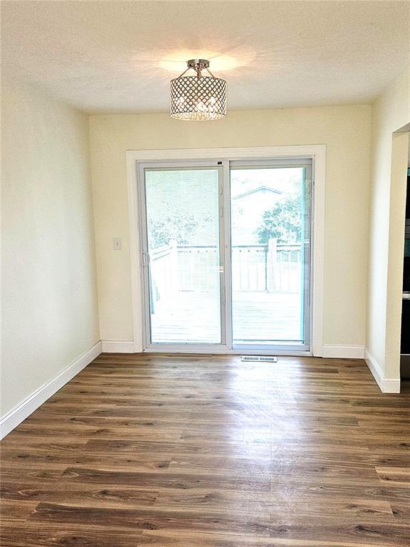 3213 Yvette Ct, Florissant, MO 63031 - unfurnished dining area with healthy amount of natural light, baseboards, dark wood-style flooring, and a textured ceiling