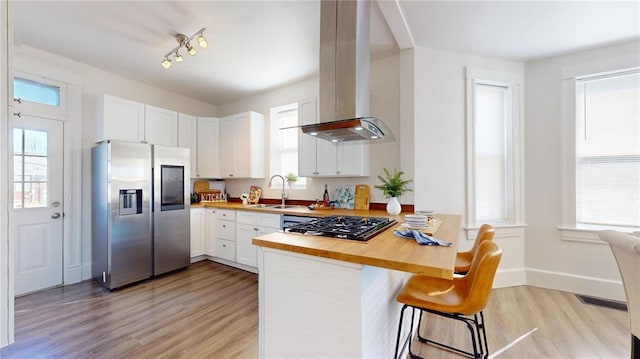 kitchen featuring stainless steel fridge, ventilation hood, a sink, wood counters, and light wood-type flooring