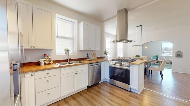 kitchen with stainless steel appliances, island exhaust hood, a sink, and butcher block countertops