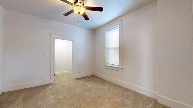 empty room featuring light carpet, ceiling fan, and baseboards