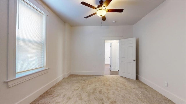 carpeted spare room with ceiling fan and baseboards