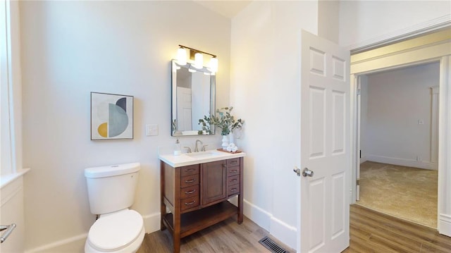 bathroom featuring wood finished floors, toilet, vanity, and baseboards