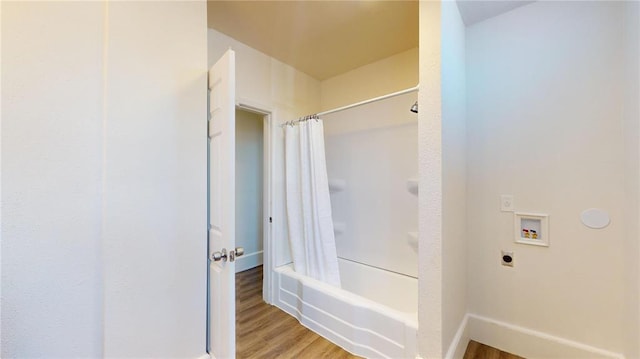 bathroom featuring wood finished floors, shower / bath combo with shower curtain, and baseboards