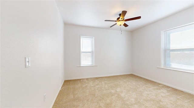 spare room featuring healthy amount of natural light, ceiling fan, light carpet, and baseboards