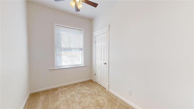 spare room featuring ceiling fan, light colored carpet, and baseboards